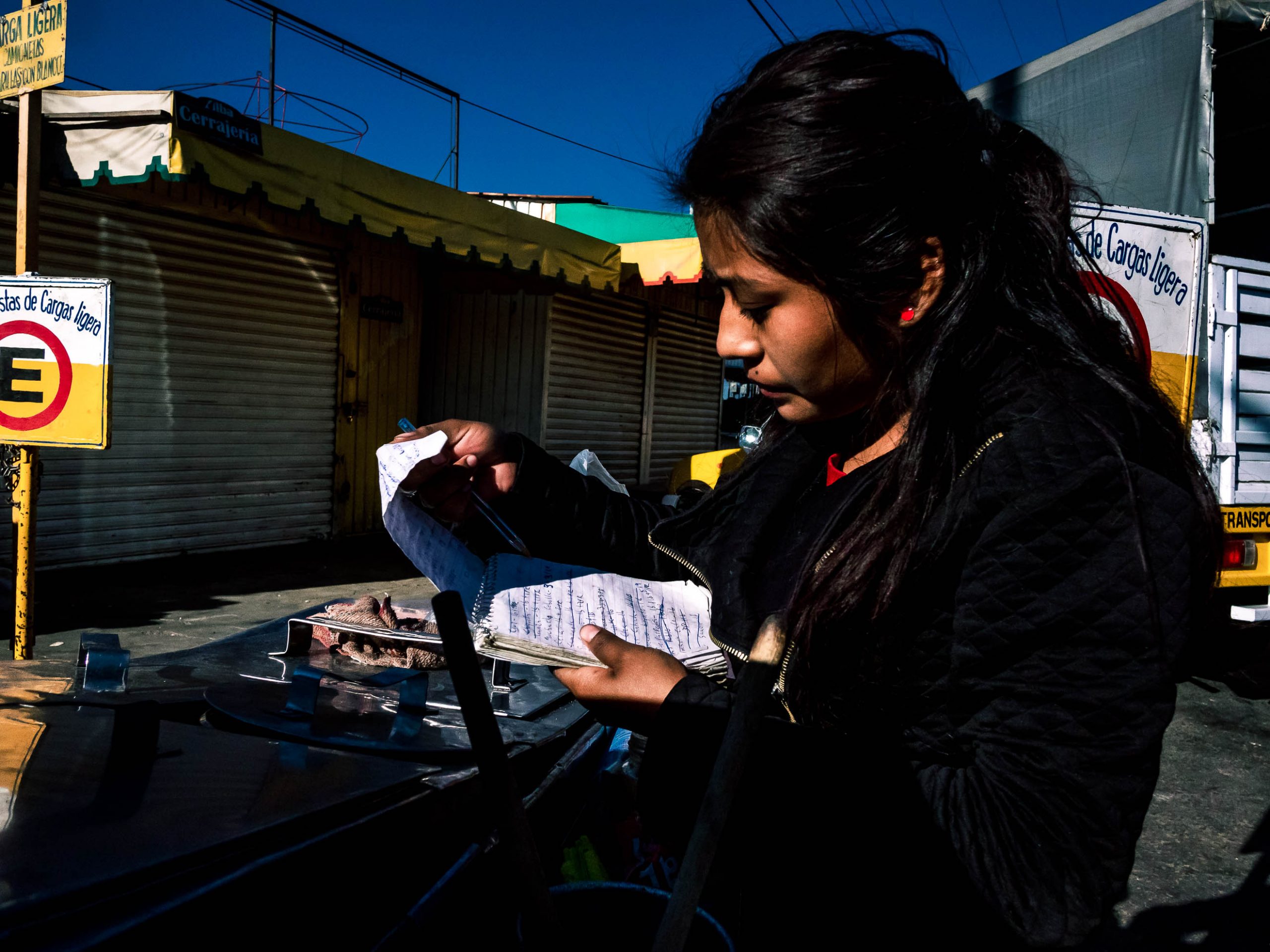 Junge Frau addiert die Einnahmen auf Mercado de Abasto in Oaxaca Mexiko